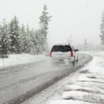 white suv on road near snow covered trees