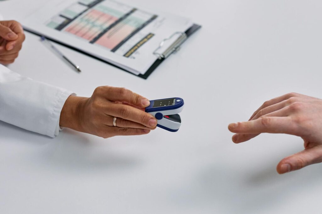 close up of doctor putting a fingertip pulse oximeter on a patients finger